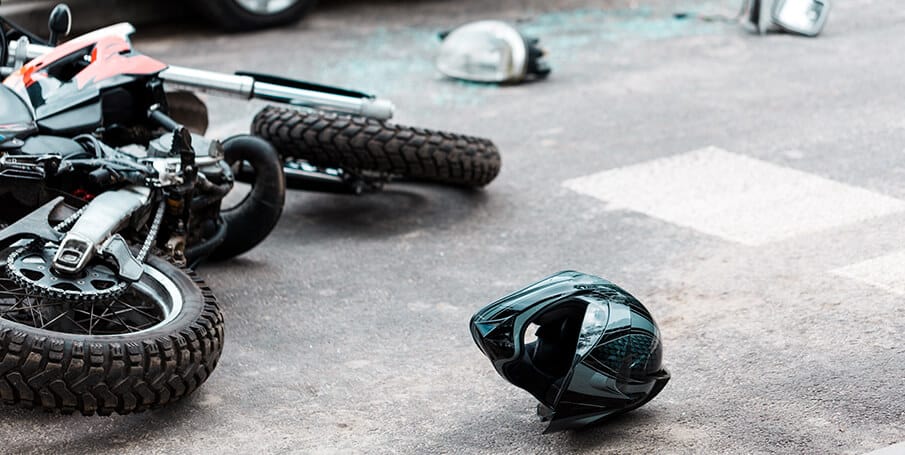 Motorcycle laid on the street with helmet alongside 