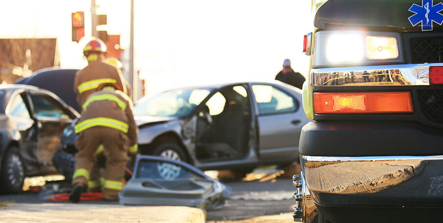 Escena de accidente automovilístico con varios vehículos y un bombero que aborda las lesiones.